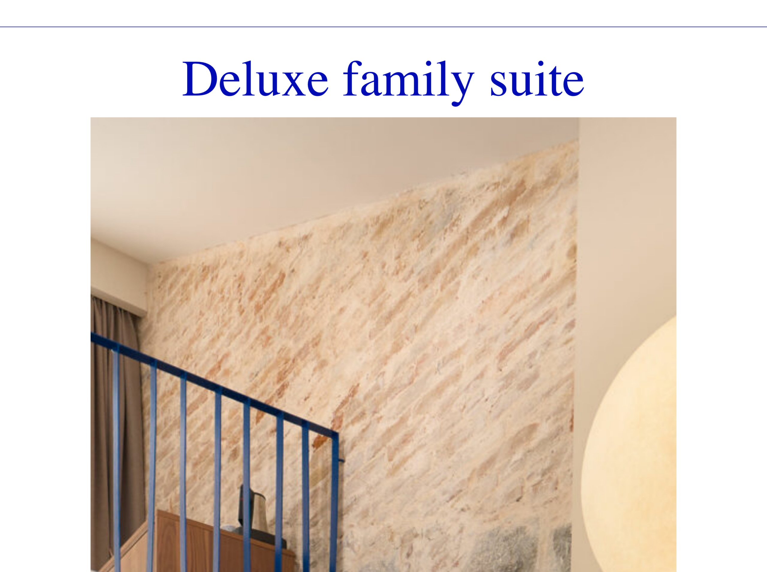 DeluxeFamilySuiteroom-detailherowithasoft-litphotoofthemarbledstonewall,bluestaircaserailingandcurtainedwindow.