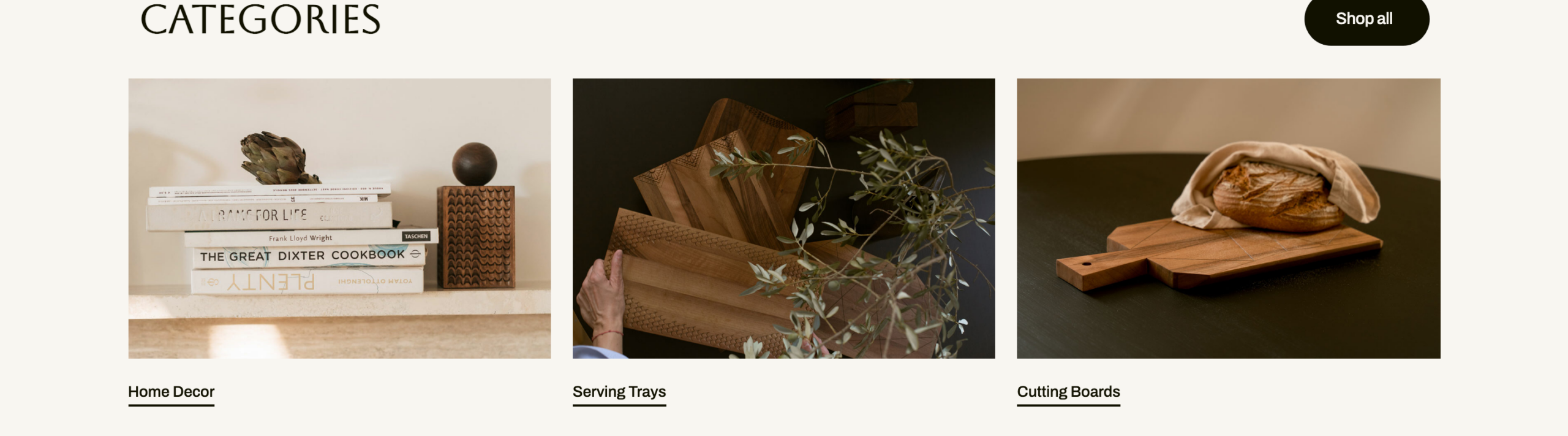 WAGAcategorysectionwiththreeeditorialcards, HomeDecorstyledwithbooks,ServingTraysheldagainstgreenery,andCuttingBoardswithfreshbread, undera'Categories'heading